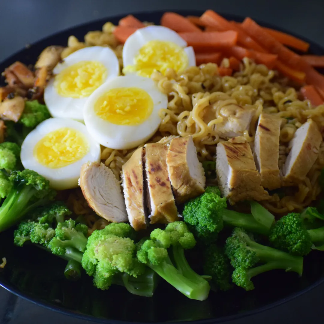 Noodle bowl with sliced chicken, boiled eggs and broccoli